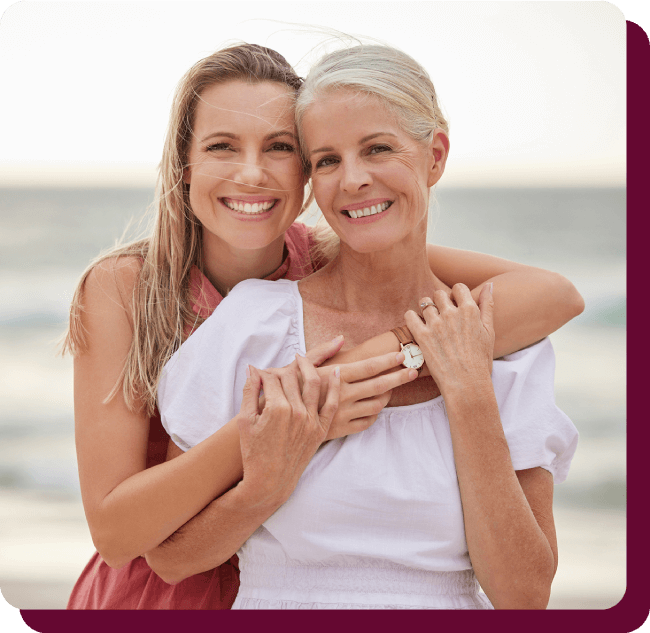 Two smiling women, mother and adult daughter, embracing outdoors representing wellness, vitality and healthy aging